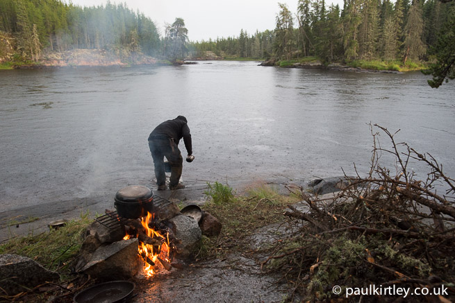 Fire and man collecting water from river in the rain