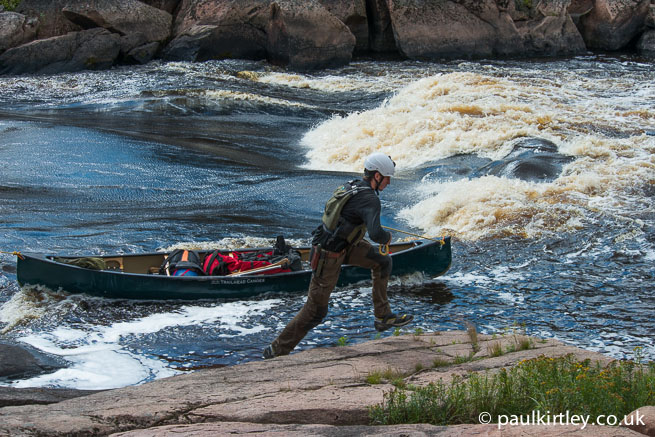 Man moving quickly while lining a canoe in powerful flow