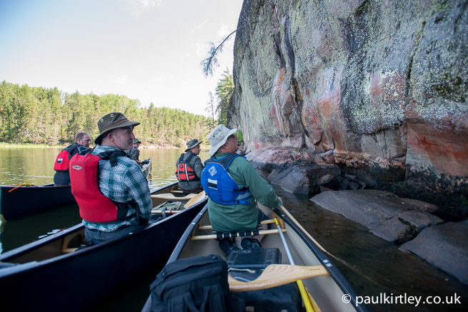 Group sitting in canoes looking at the Artery Lake pictographs