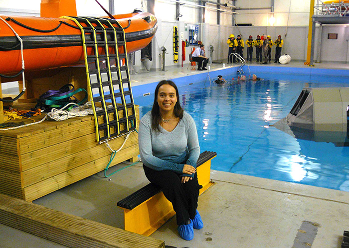 Dr Sarita Robinson sitting in front of training pool for helicopter underwater evacuation training and life rafts