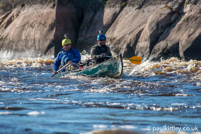Ray Goodwin in the stern of a boat with a bow paddler on some rapids on the Bloodvein River