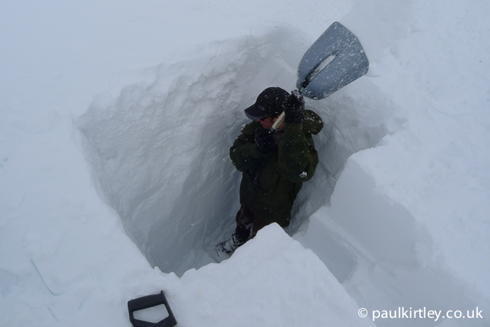 Man in a the two meter deep trench in the snow shovelling