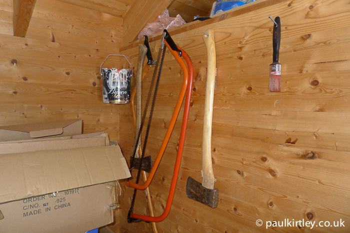 Axes and bow saws hanging on woodshed wall