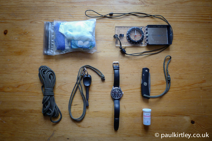 small first aid kit, compass, paracord, FireSteel, automatic watch, foldking knife, lip salve - important on-person items
