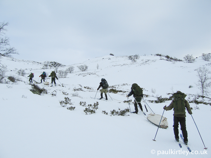 Skiers struggling uphill with laden pulks