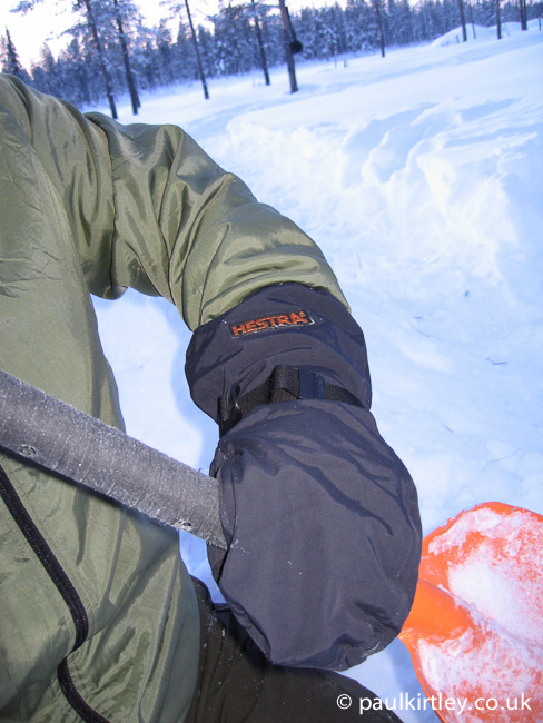 Hestra shell mitts on hand grasping orange Black Diamond snow shovel