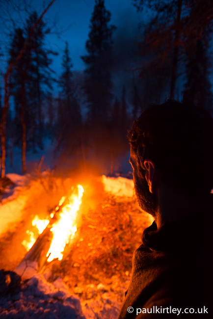 Man overlooking a burning long log fire