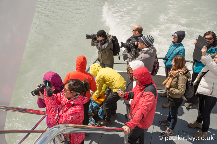 people standing on the rear deck of a boat taking photographs