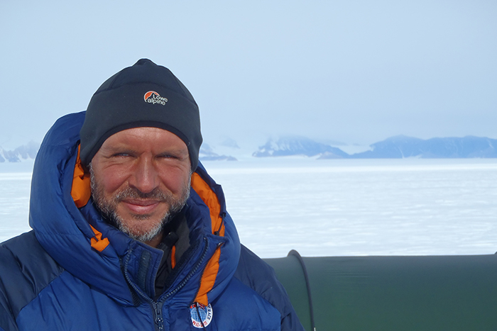 Lou Rudd, face tanned, wearing hat and duvet jacket against backdrop of polar landscape