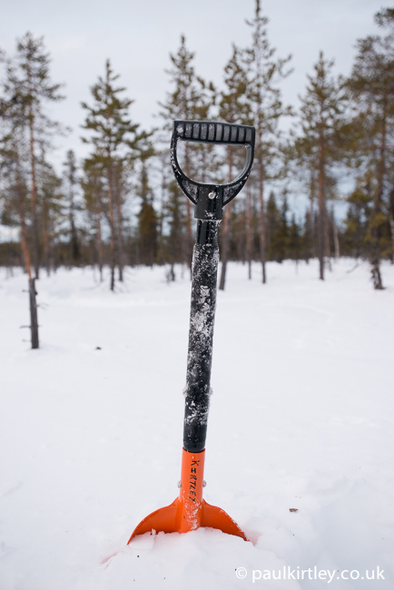 Snow shovel with snow on the shaft of the handle