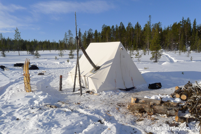 Snowtrekker tent in use in Sweden with wood processing area in front