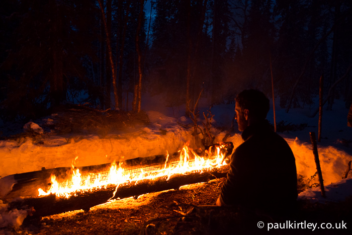Man in front of big fire in woods