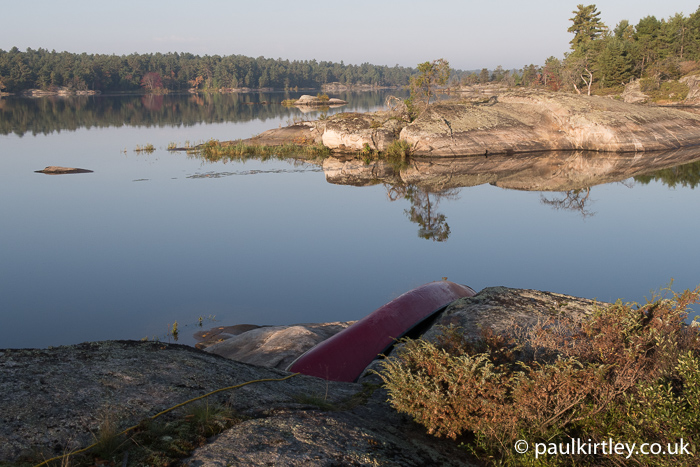 Canoe overturned on rocks with perfectly still water