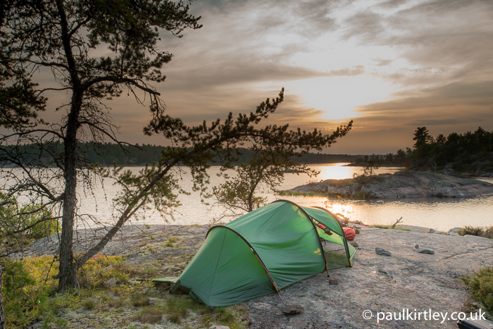 Tunnel tent on flat rock with sunset and Jack Pine