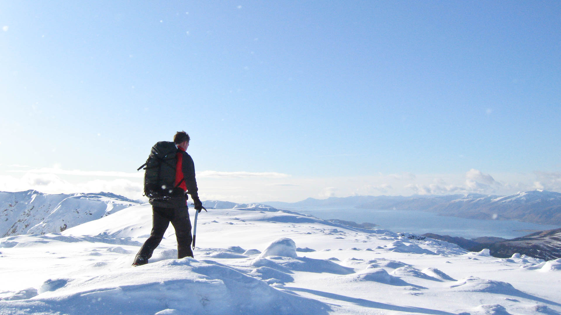 Man walking on broad snowy ridge west coast Scotland