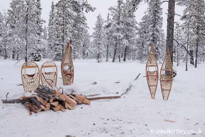 Snowshoes and firewood stacked on snow