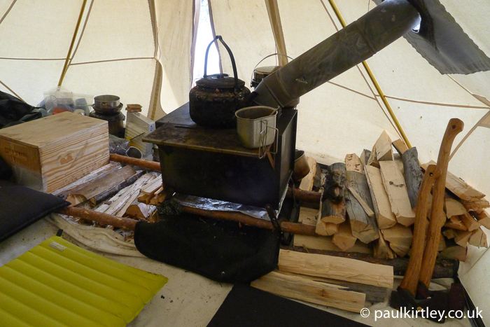 Inside of heated tent, including stove and stacked firewood