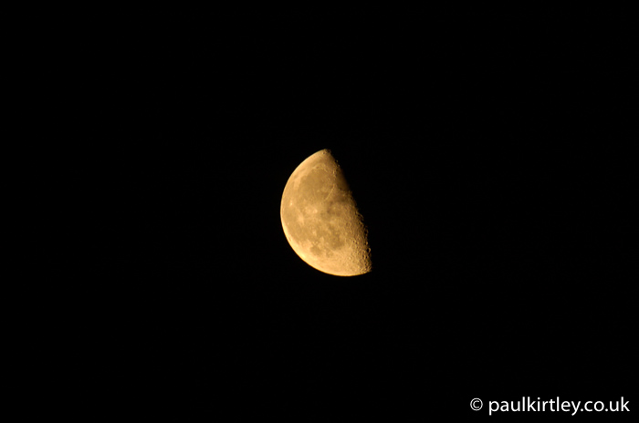 Quarter moon illuminated against black sky
