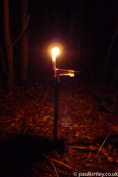 candle in an improvised holder made from a stick and some bark