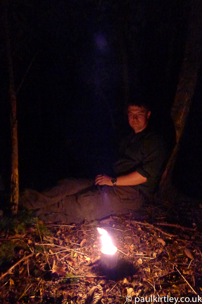 Man sitting at base of tree in glow of big candle