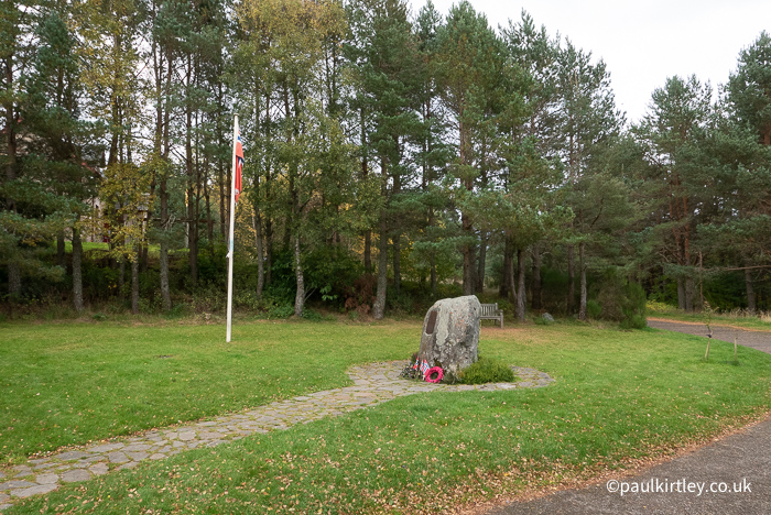 Stone with wreaths and nearby Norwegian flag