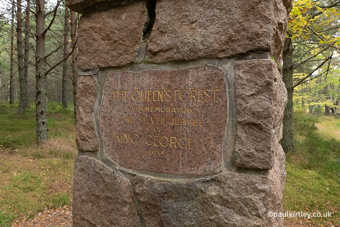 Plaque attached to stone structure stating Queen's Forest.