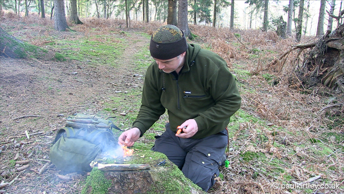 Man tinkering with small fire of fatwood shavings