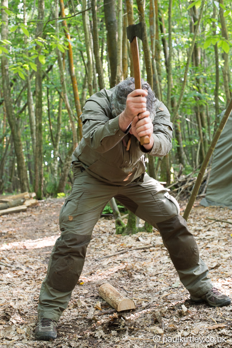 Man dressed in green using advanced dynamic splitting technique with popular bushcraft axe size