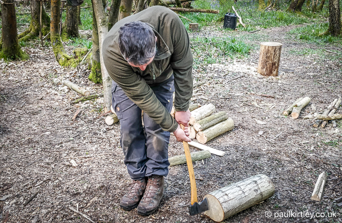 Man undertaking unusual horizontal dynamic splitting technique with axe