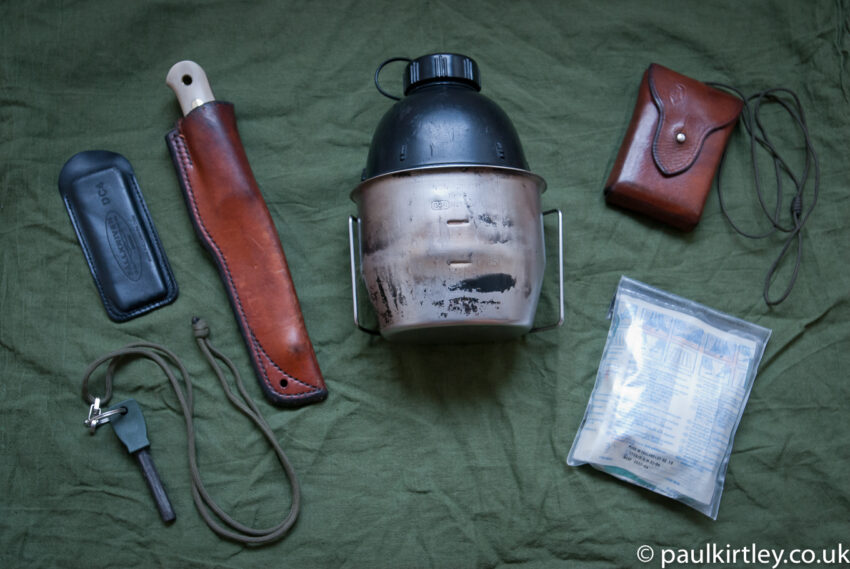 Paul Kirtley's essential wilderenss equipment - firesteel, whetstone, belt knife, metal mug, bottle, compass, first aid kit