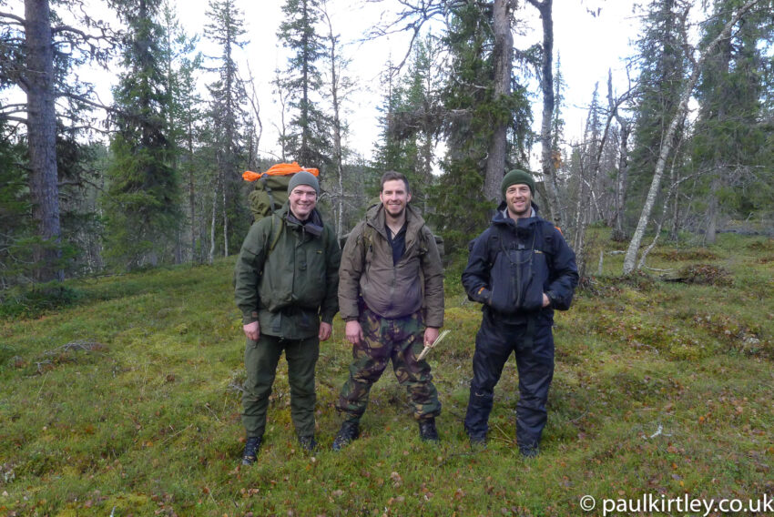 Three well-equipped outdoorsmen looking happy in the northern forest