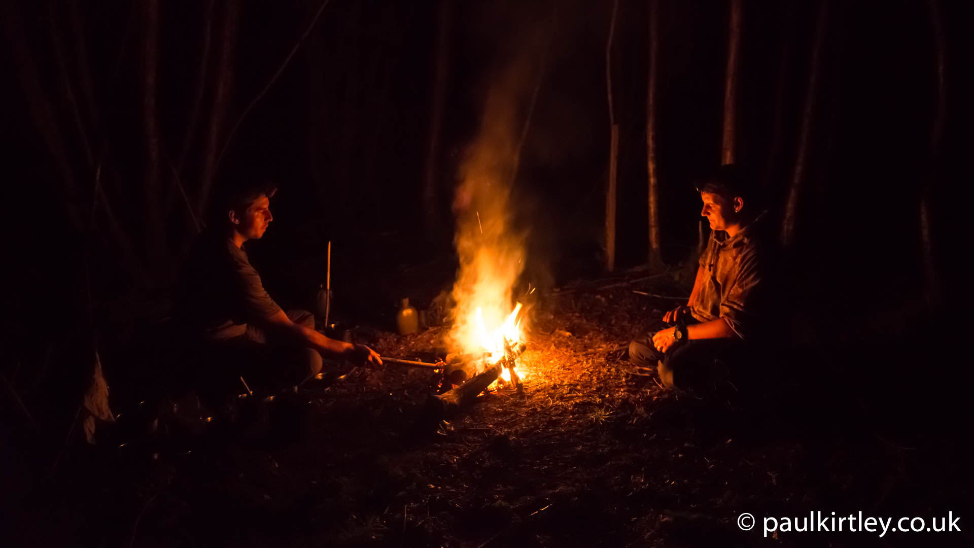 Primitive Bushcraft Shelter In The Forest With A Campfire Inside