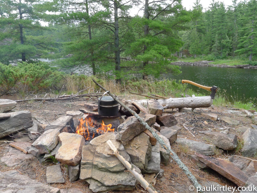 A rocky camping spot on the Canadian Shield, with an axe in a log