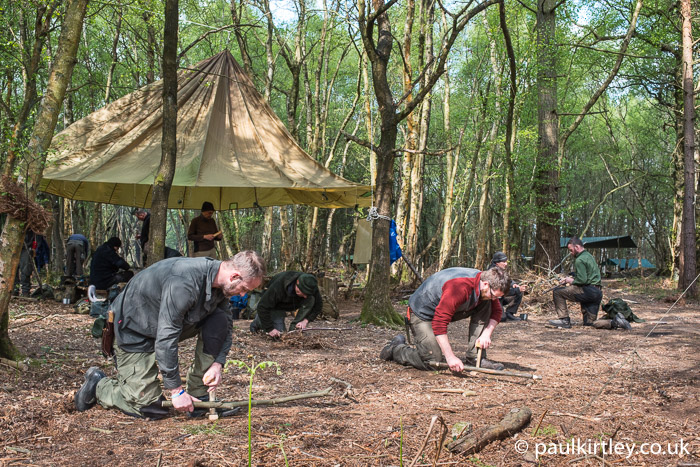 Guys bow drilling in the woods