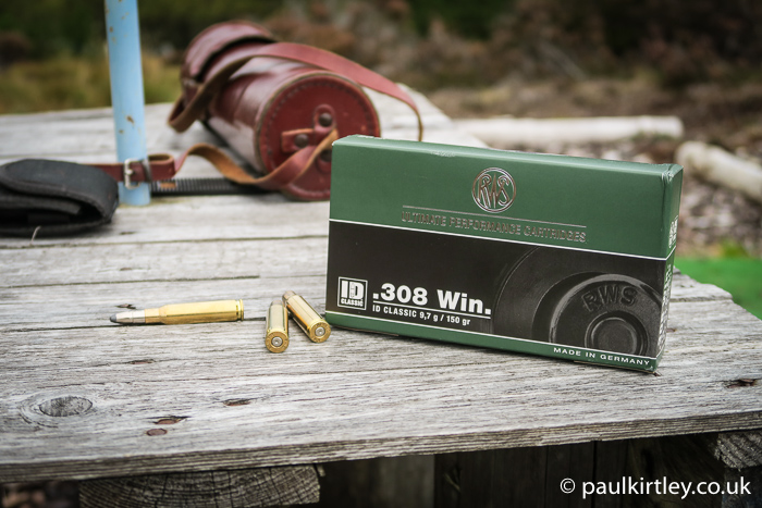 RWS .308 win ammunition and stlaker's spotting scope in leather case on wooden table.
