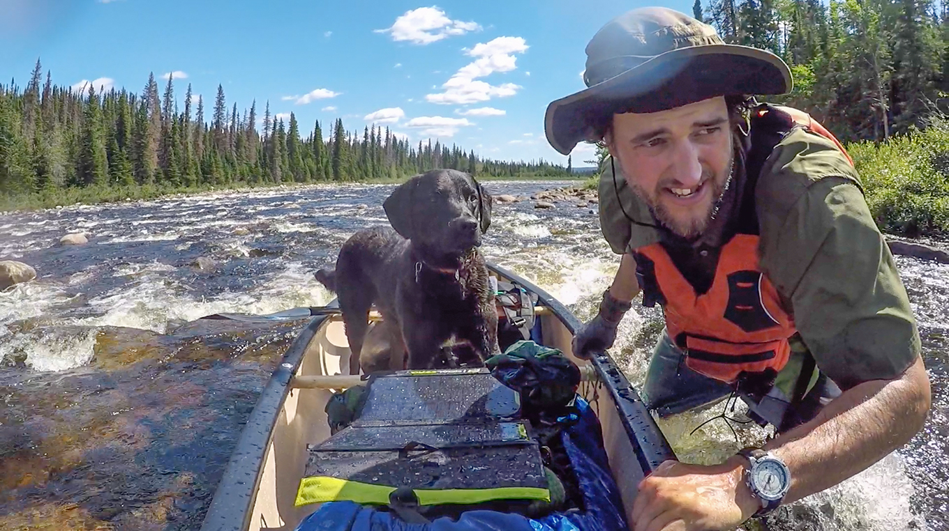 Justin Barbour and his dog, Saku, with canoe in river