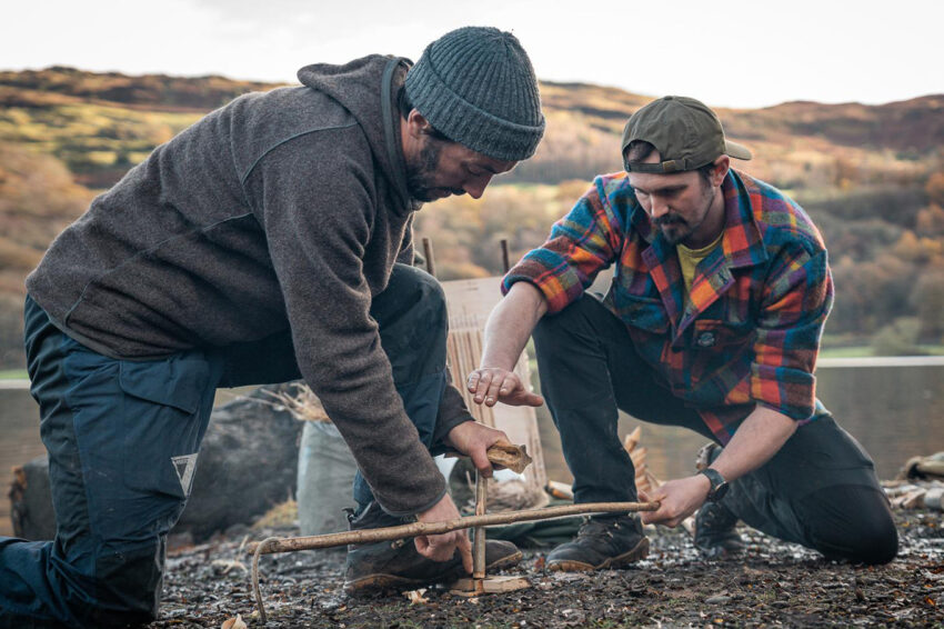 Two bushcraft instructors working bow-drill as a pair