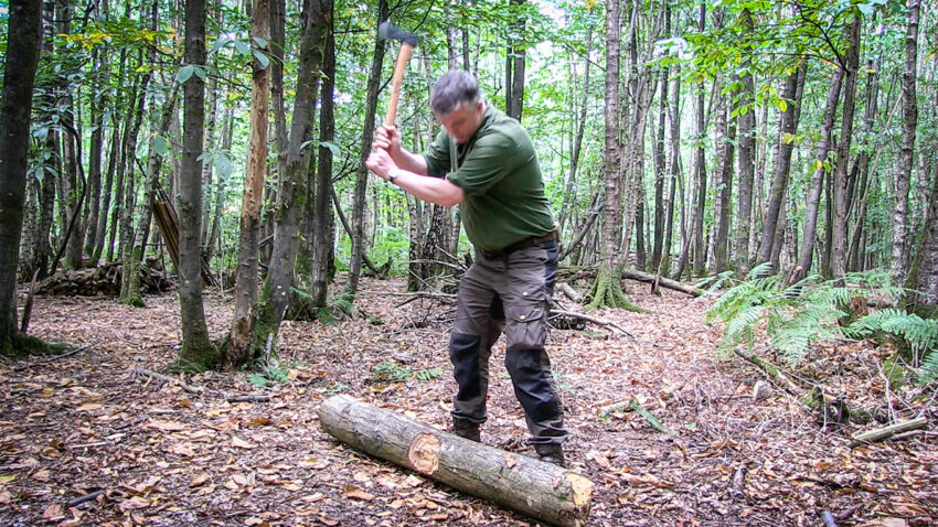 Man bucking a log with an axe